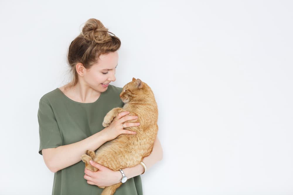 Woman holding a cat, cat is relaxed