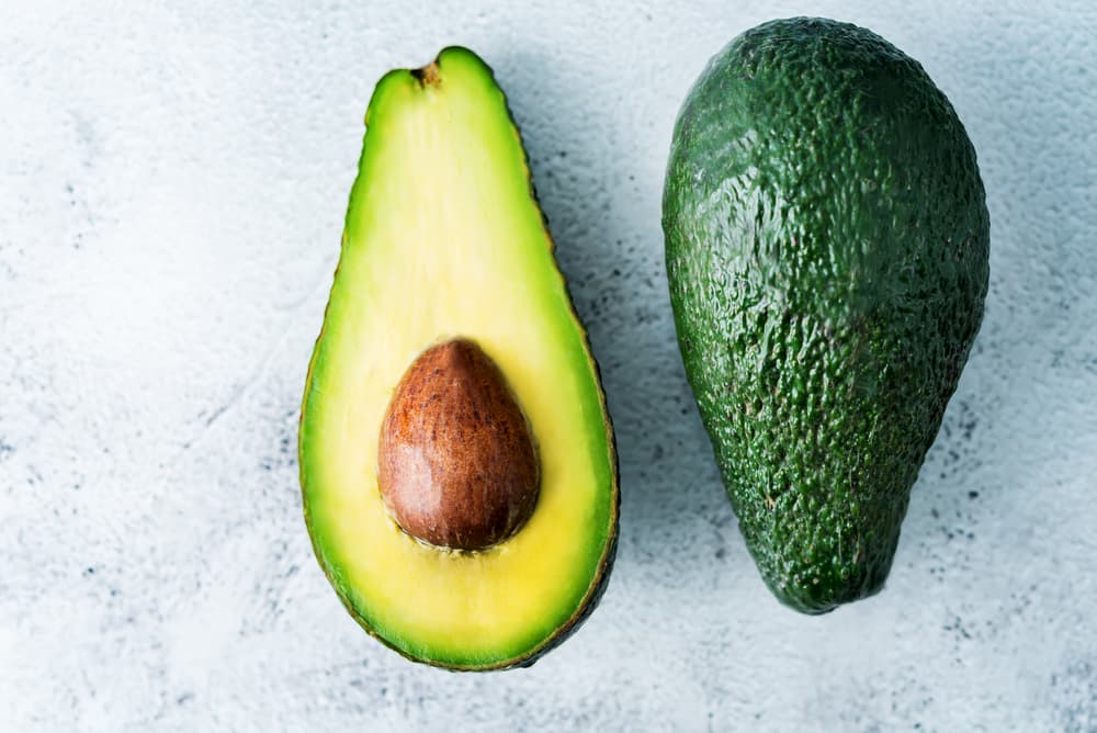 Sliced avocado in half on a grey backdrop