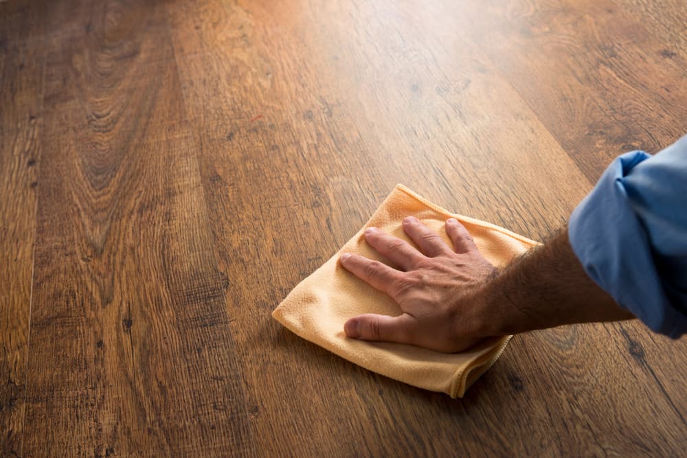 Man cleaning wood floor with cloth