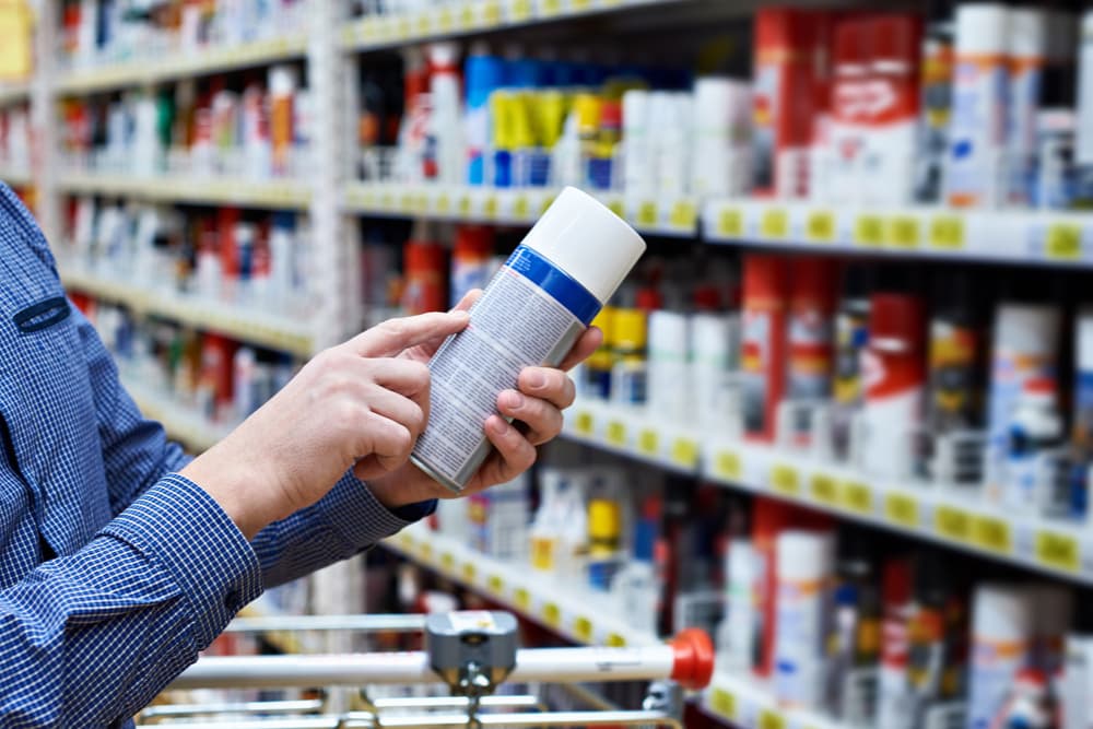 Man in aisle of shop checking a label
