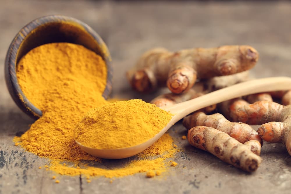 Powdered and fresh turmeric on a wooden board