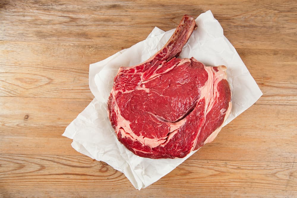 Raw steak with bone on butcher paper on the table