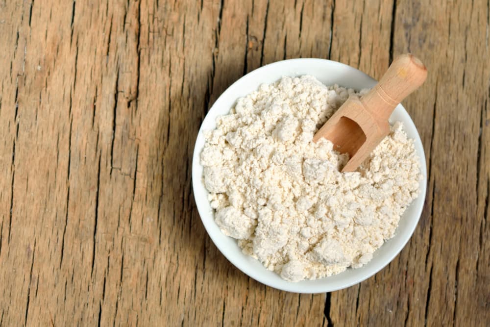 Colloidal oatmeal powder in a bowl on a wooden table