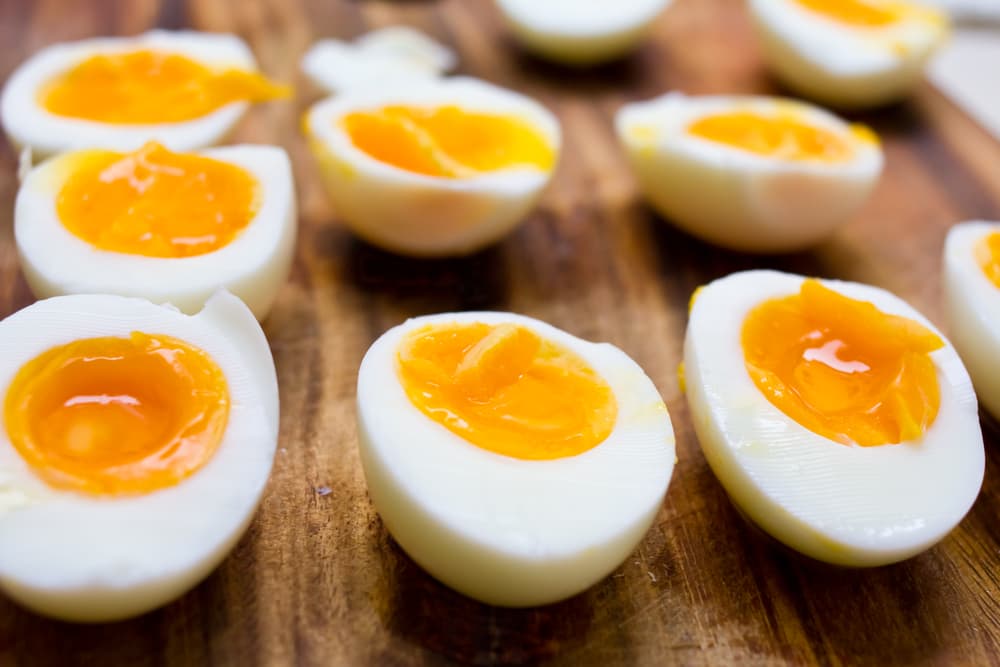Egg yolks and hard boiled egg sitting on a wooden board