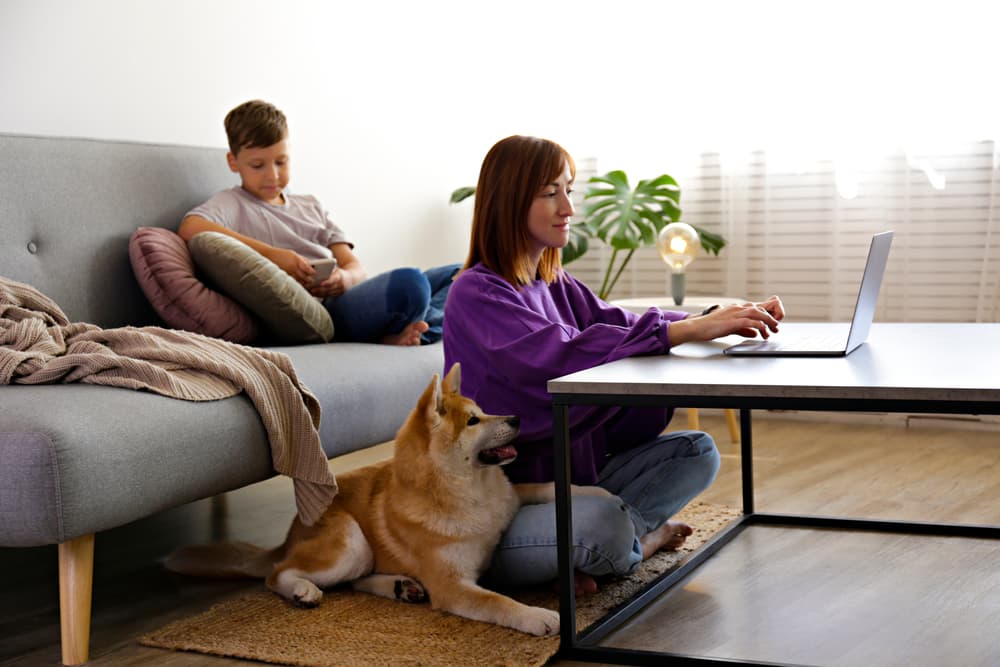 Dog laying on ground next to owner by the table not on the couch