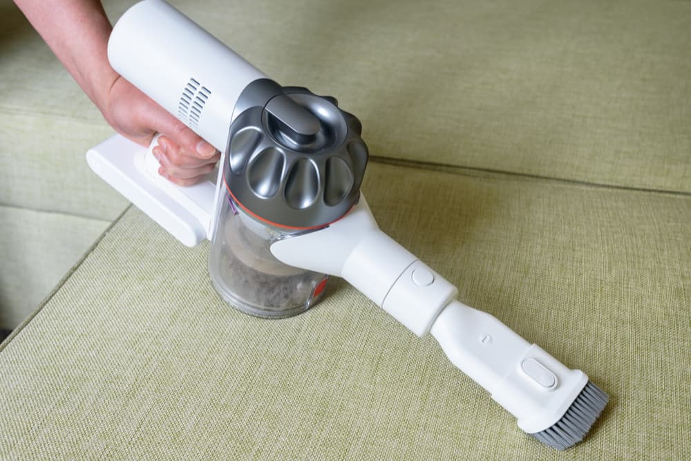 Vacuuming a couch cushion on a cute green couch