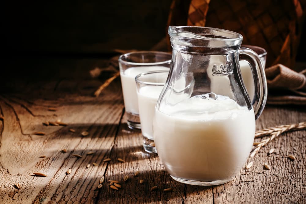 Fresh goat milk in a clear pitcher on a table