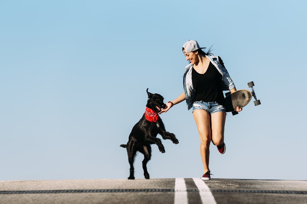 Girl running with her dog on the road with skateboard