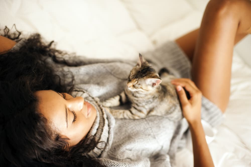 Woman in bed snuggling her cat