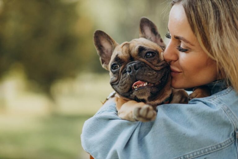 Woman holds her French Bulldog at the park