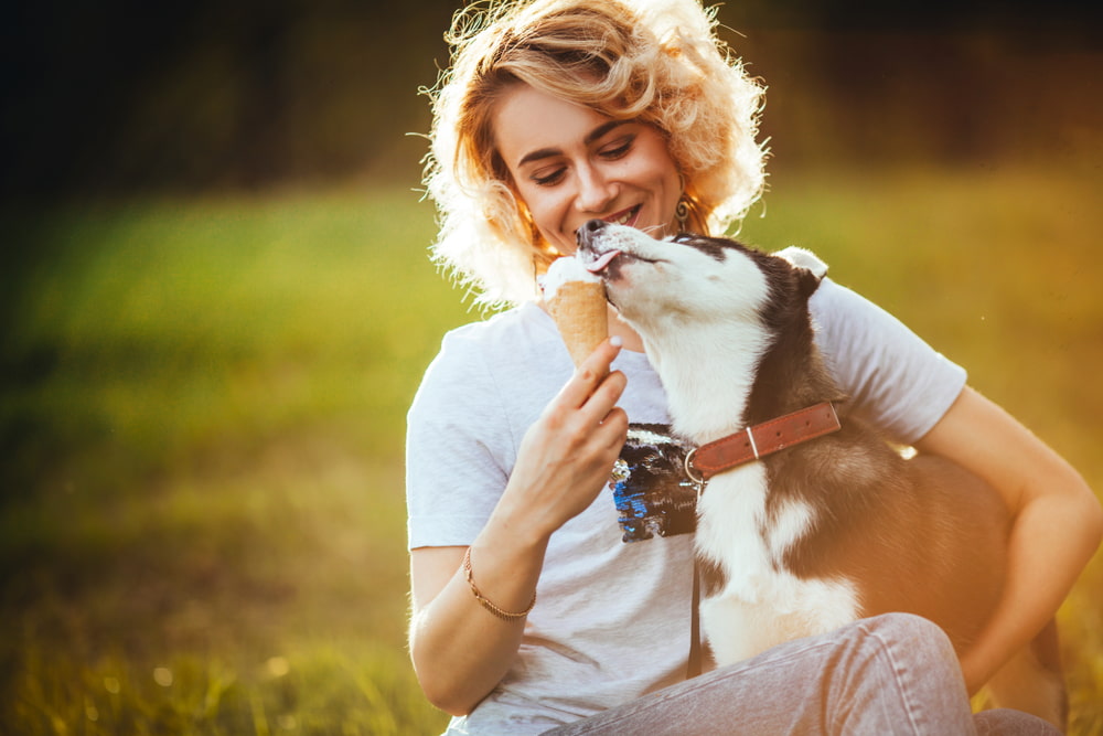 woman sharing ice cream with dog