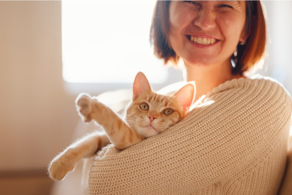 Owner holding her cat laughing